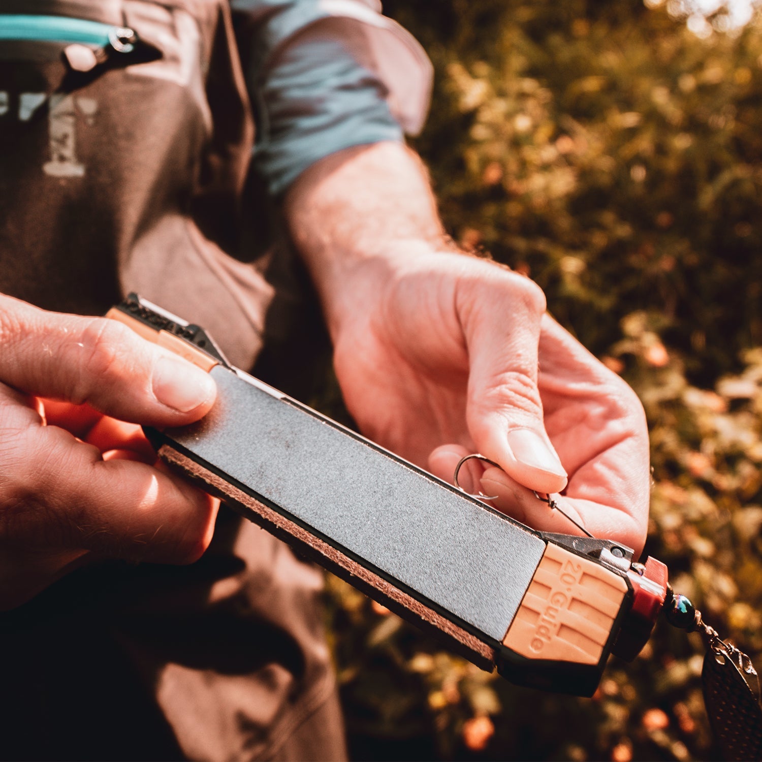 Worksharp Guided Field Sharpener sharpening a fish hook in the grooved ceramic rod